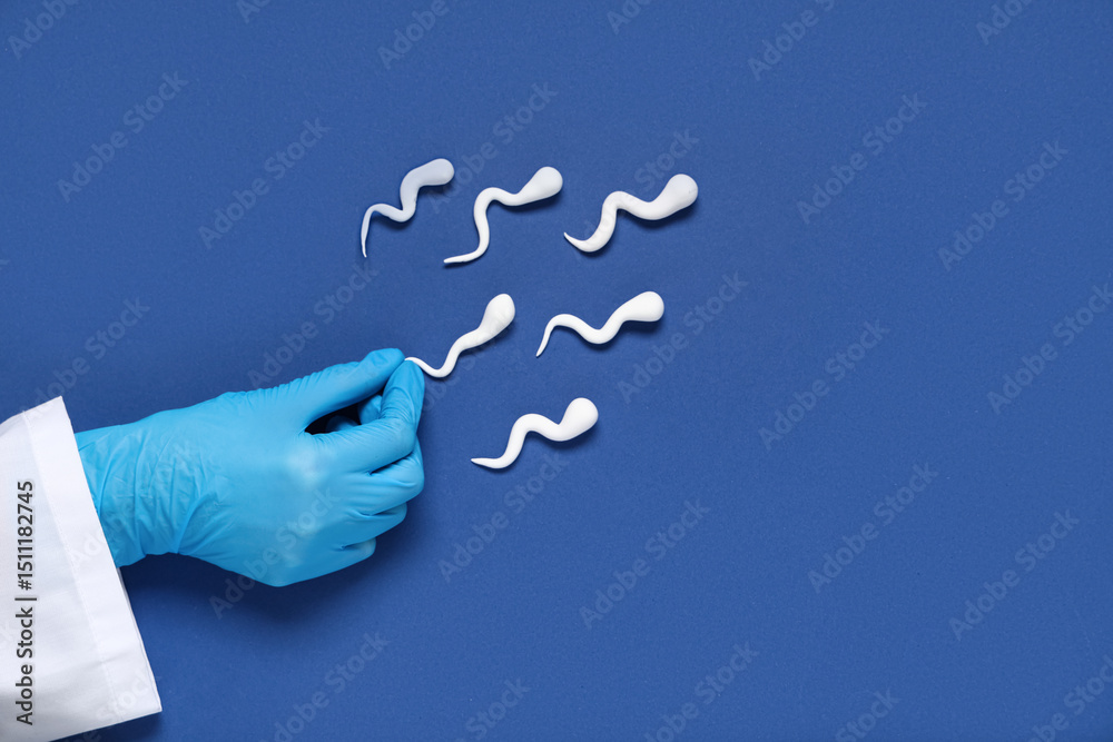 Doctor's hand with sperm cells on blue background Doctor's hand with sperm cells on blue background