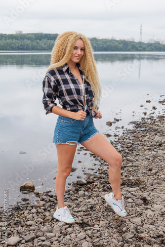 Young beautiful woman standing on the river shore