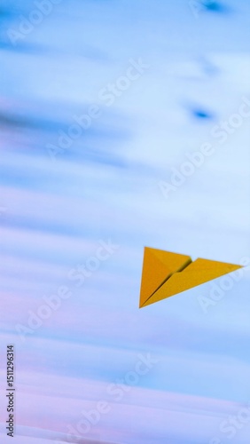 Yellow paper airplane flying over pastel sky background....