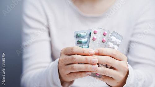 Close up of woman holding blister packs of assorted capsules and tablets showing multiple medications for health treatment