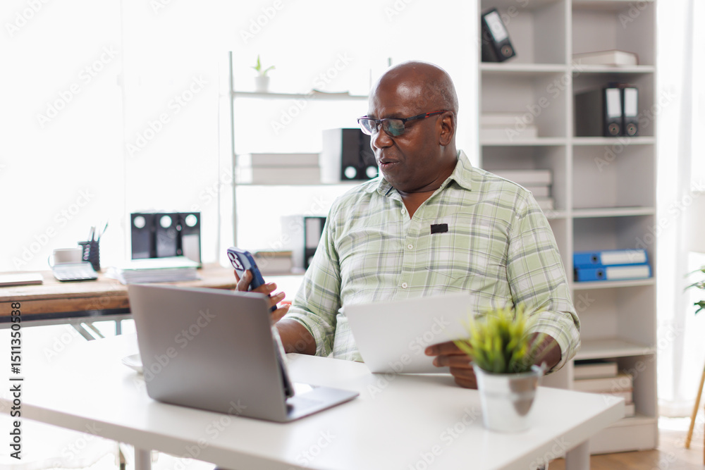 Senior man working with papers and Laptop in workplace reading Documents, enjoying eemote work and Business on retirement.
Senior man working with papers and Laptop in workplace reading Documents, enjoying eemote work and Business on retirement.