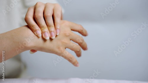 Asian woman massaging her own hand with relaxed expression promoting self care and stress relief through gentle pressure therapy