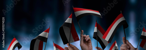 Yemen flags in their hands on a blurred urban background