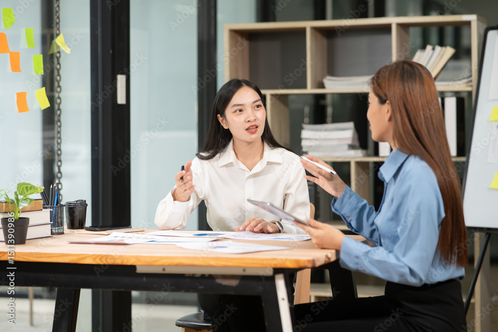 Fototapeta premium Asian businesswoman discussing documents and graphs in the office