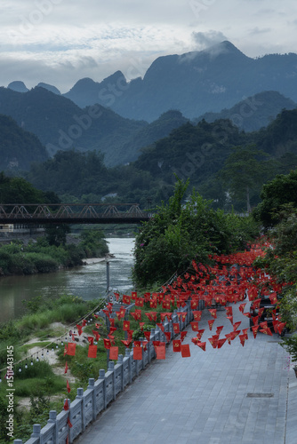 Fototapeta Naklejka Na Ścianę i Meble -  A small street by the river, decorated with Vietnamese national flags in the center of Ha Giang town of northern Vietnam