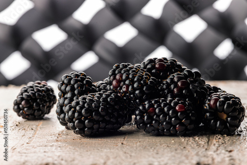 Glossy ripe blackberries on rustic board with geometric bokeh