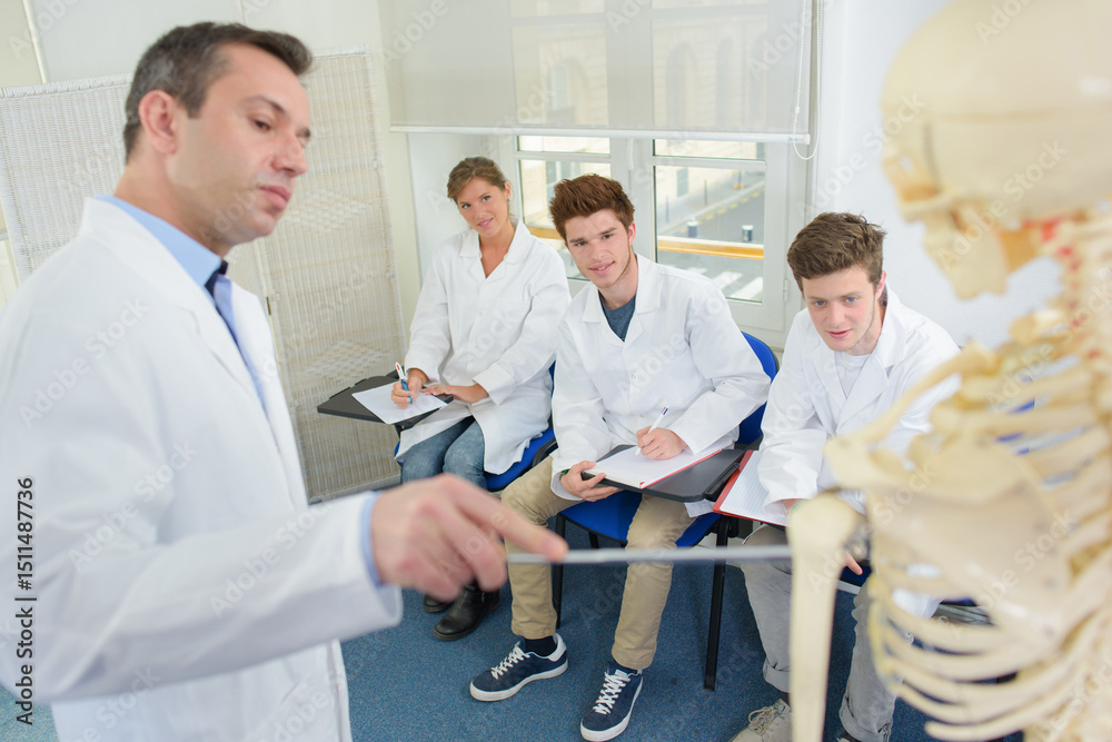 Obraz premium Medical students listening to teacher with skeleton