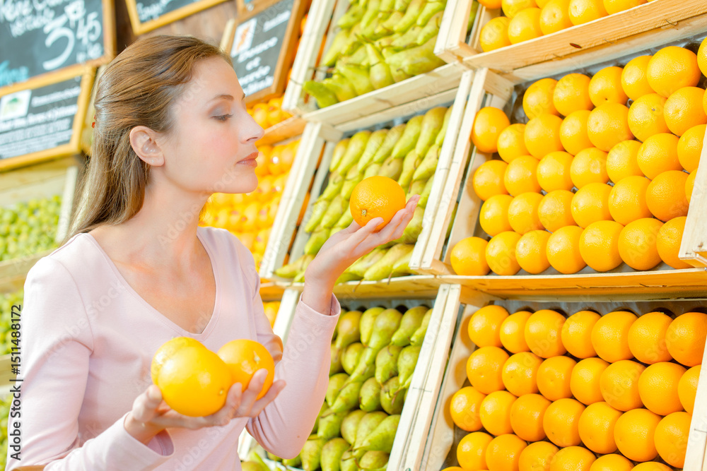 Obraz premium Lady holding oranges in greengrocers