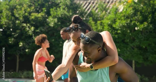 Diverse friends enjoying piggyback rides and laughter by pool on sunny day