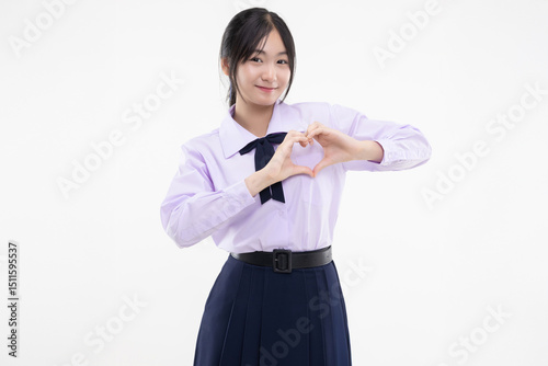 Happy pretty Asian student girl in school uniform showing heart shape hand sign isolated on white background.