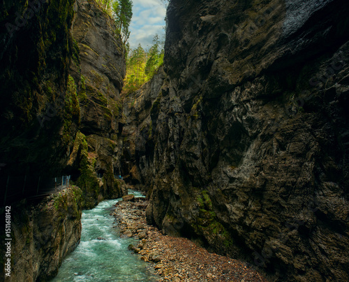 Mystical photo of Partnachklamm Gorge in Bavaria, Germany, with emerald green water, moss-covered cliffs, and atmospheric, dramatic natural scenery. vertical panorama