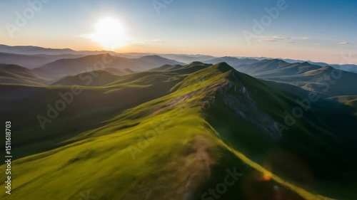 Aerial view of lush green mountains, sunrise illuminating the peaks, serene landscape perfect for nature themes.