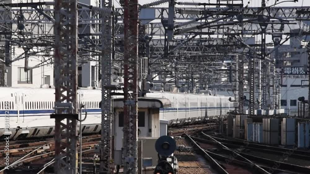 High-Speed Shinkansen Bullet Train Departing from Urban Railway Station in Osaka, Japan with Overhead Cables and Metal Infrastructure High-Speed Shinkansen Bullet Train Departing from Urban Railway Station in Osaka, Japan with Overhead Cables and Metal Infrastructure