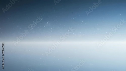 Tiny particles slowly float in a gradient of blue and white light, creating calming, atmospheric effect. bokeh