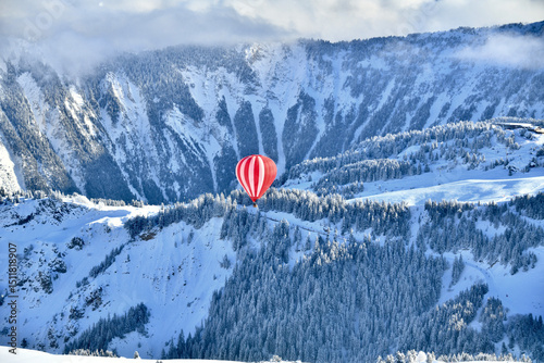 Red hot air balloon in blue sky in french Alps by winter