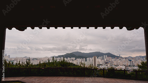 Panoramic cityscape of Busan framed by pavilion roof at Dongnae Eup Fortress, South Korea photo