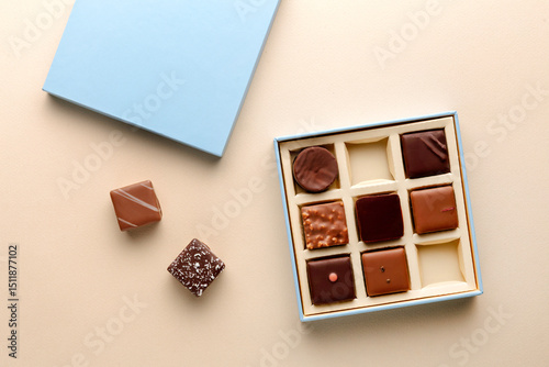 Minimal flatlay of open box with chocolate squares on beige background, elegant candy dessert packaging mockup concept