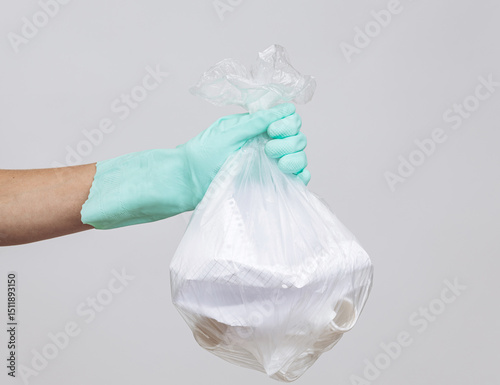 Hand in Rubber Glove Holding Plastic Bag with Takeaway Food Containers on Neutral Background