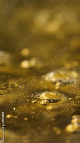 Close up of Golden bubbles in a thick liquid, abstract visual. Vertical video