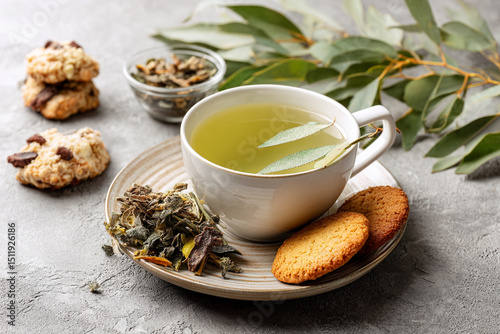 Tea ceremony: a cup of green tea, dried leaves and cookies nearby photo