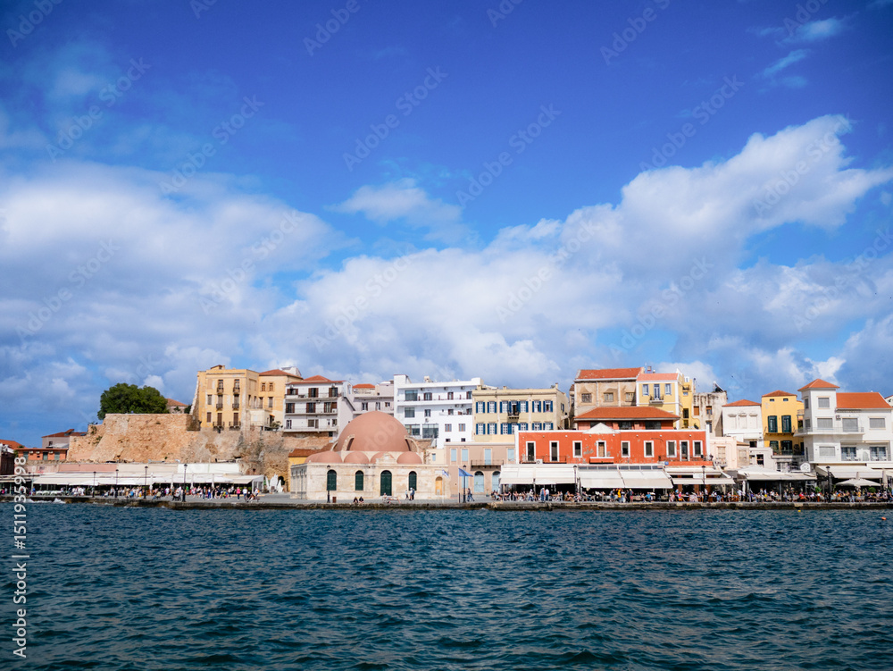 Fototapeta premium Scenic view of the Old Port in Chania, Crete, Greece, with Venetian architecture, calm waters, and a vibrant waterfront. A timeless Mediterranean coastal destination.