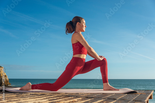 Woman Practicing Yoga Outdoors by the Ocean on a Sunny Day, Low Lunge.