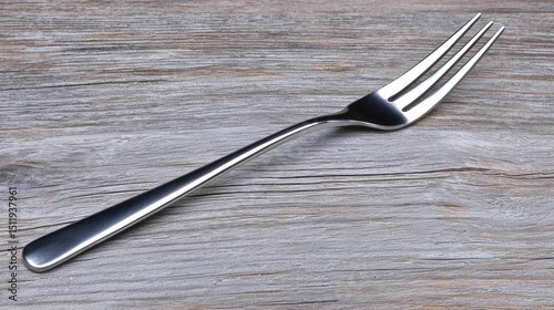A fork with a silver handle and tines rests on a wooden surface.