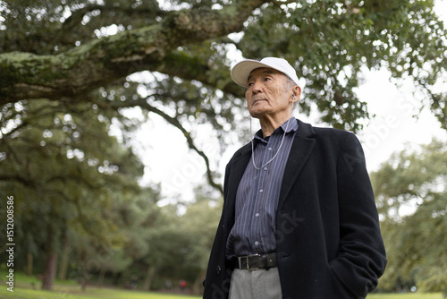 Senior man enjoying music in park wearing white cap
