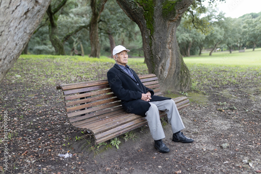 Fototapeta premium Senior man relaxing on park bench enjoying nature