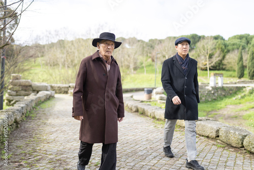 Two senior men walking in cobblestone path at park