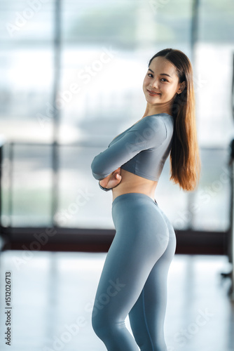 Free Download A woman is wearing blue leggings and a grey shirt. She is standing in a room with a window - GFXLoad
