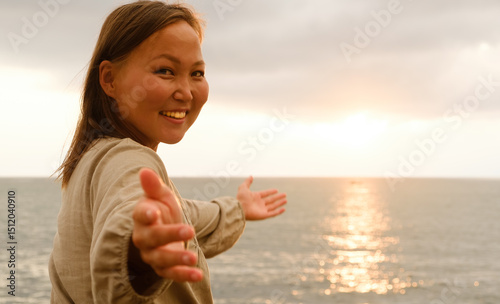 A cheerful woman joyfully welcomes a stunning sunset view over the vast ocean, radiating positivity and peace
