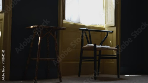 A black chair sits in front of a yellow wall. The chair is empty and the room is dark