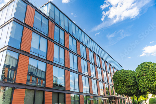 Green trees on the grounds against the backdrop of office buildings and blue skies. Outdoor recreation area near the business center.