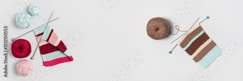 Brown beige vinous and turquoise piece of striped knitting with knitting needles and balls of thread on gray background. Homemade needlework and knitting of warm, clothes and toys. Banner