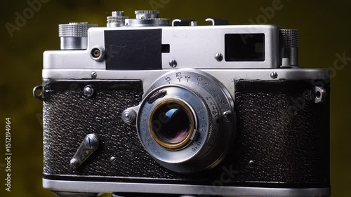 An old camera slowly rotates around its axis, against an old background.
