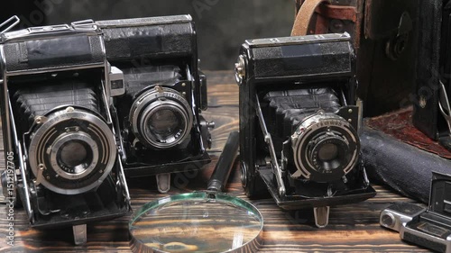 Old cameras in a composition on a wooden background, slowly moving in a horizontal plane.