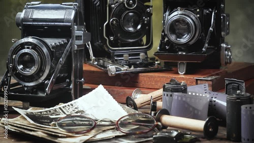 Old cameras in a composition on a wooden background, slowly moving in a horizontal plane.