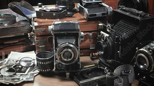 Old cameras in a composition on a wooden background, slowly moving in a horizontal plane.