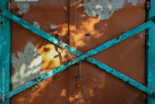  A close-up of a rusty metal surface with blue diagonal bars forming an 'X' shape, showcasing the contrast between corrosion and structure