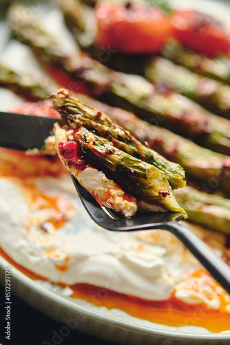 Pieces of green baked asparagus with yogurt dressing on a fork