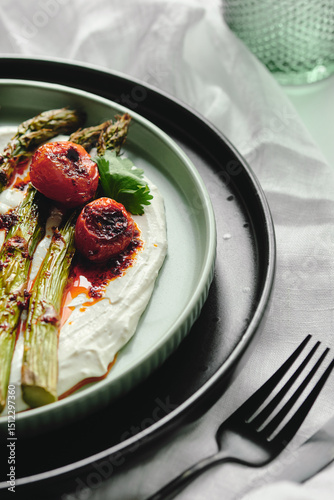 Healthy snack: roasted asparagus with yogurt and roasted tomatoes, spices and fresh herbs