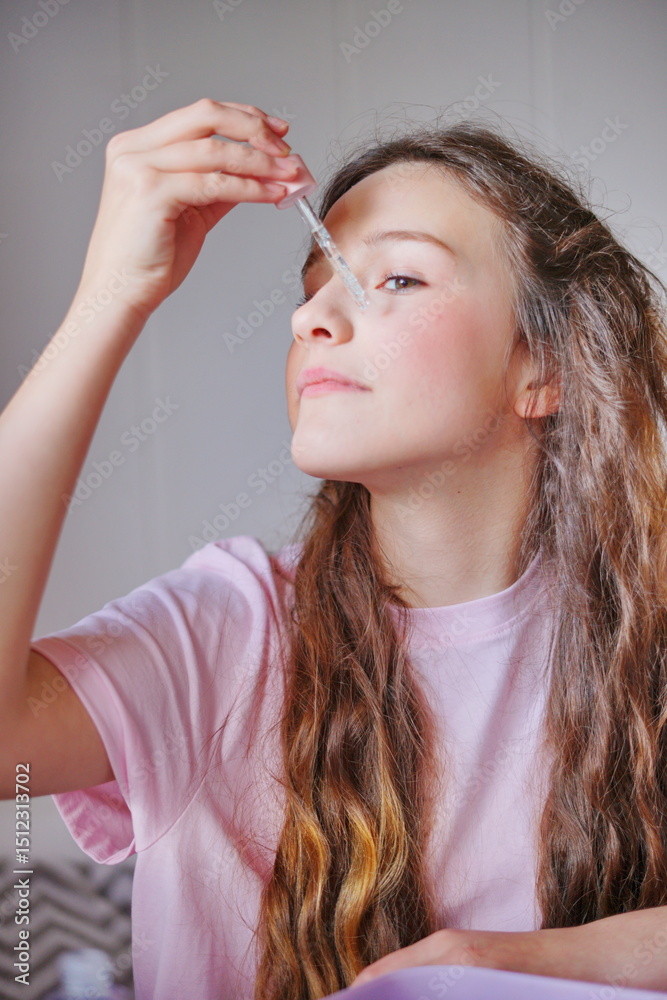 Fototapeta premium Girl applying serum to her face in a cozy indoor setting while enjoying some personal care time in the morning