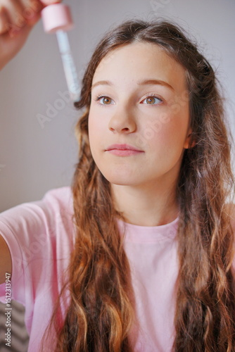 Young girl with cute long hair applying beauty product in a cozy indoor setting during the afternoon light