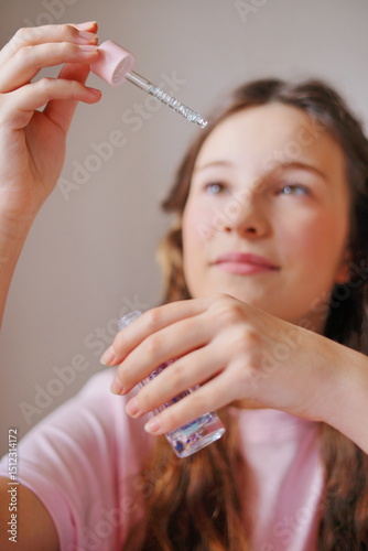 Girl happily experimenting with a dropper of colorful liquid while sitting at a table in a cozy indoor setting during the afternoon