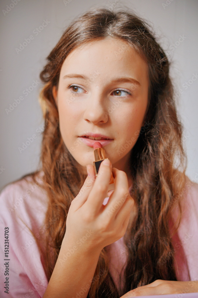 Girl applying lipstick for a fun and creative makeup session at home during a bright afternoon Girl applying lipstick for a fun and creative makeup session at home during a bright afternoon