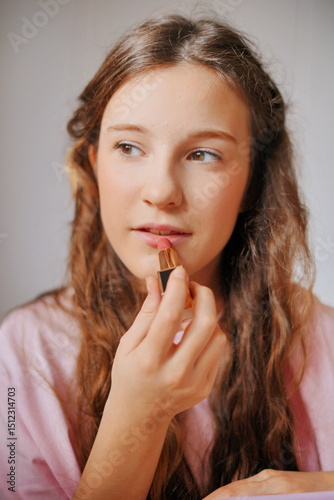Girl applying lipstick for a fun and creative makeup session at home during a bright afternoon