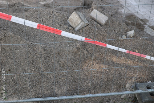 A red and white striped fence is in front of a pile of rubble