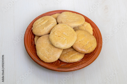 Tasty crispy Bakarkhani on a clay plate on a light wooden surface. Baqarkhani is a thick spiced flatbread that is part of Mughlai cuisine. photo