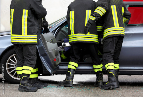 Fire brigade removing car door to free injured person after accident photo